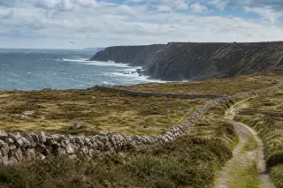Falaises de granit et landes battues par le vent à la Hague, Cotentin, avec mer agitée et murets de pierre