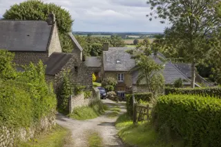 hameau normand de Branville-Hague avec maisons en pierre, chemin creux, arbres et lumière douce
