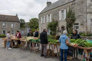 Marché local dans un village du Cotentin avec habitants, étals de produits régionaux et ambiance conviviale