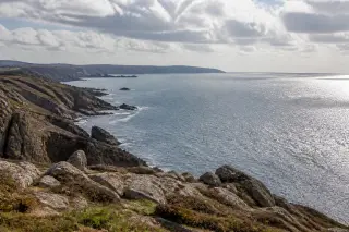 Open coastal panorama at Pointe de la Hague with rocky shoreline, wide sea horizon, and dramatic changing light.